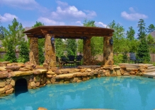 Tropical-pool-with-cave-arbor-with-stone-column-bases
