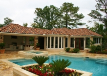 mediterranean-style-pool-and-spa-surrounded-by-small-flower-beds-and-patio-cover-with-outdoor-kitchen